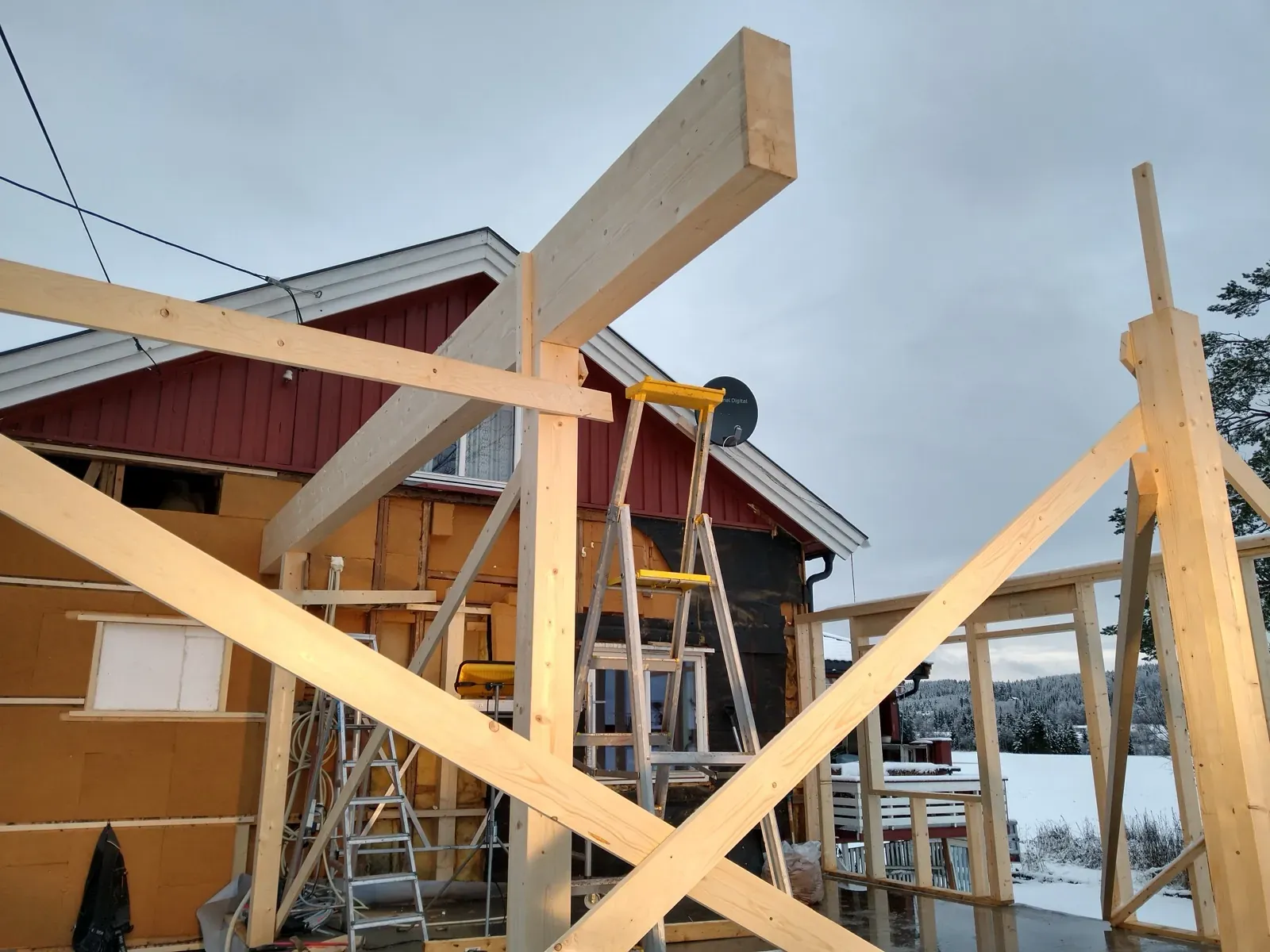 Bindingsverk for tilbygg reist i november med gylden vinterlys og snølandskap