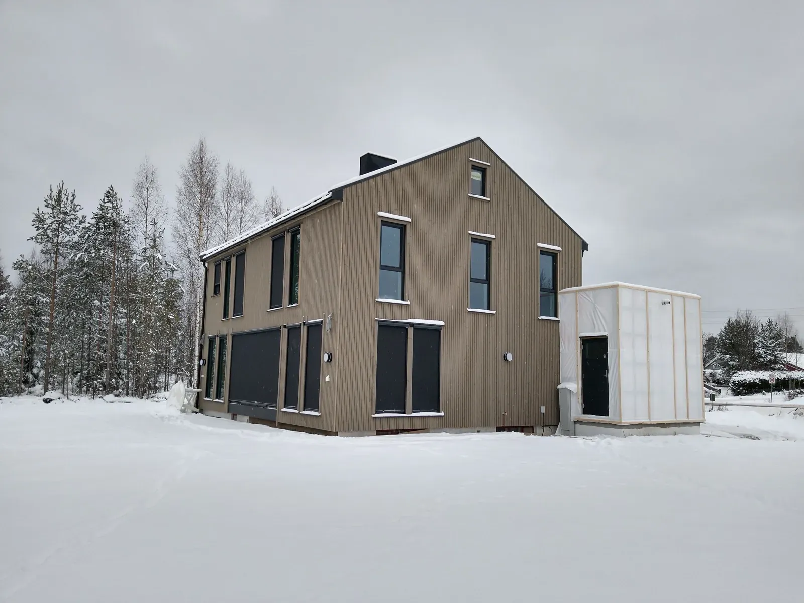 Ferdig totalrenovert enebolig med moderne grå-brun trefasade i vinterlandskap